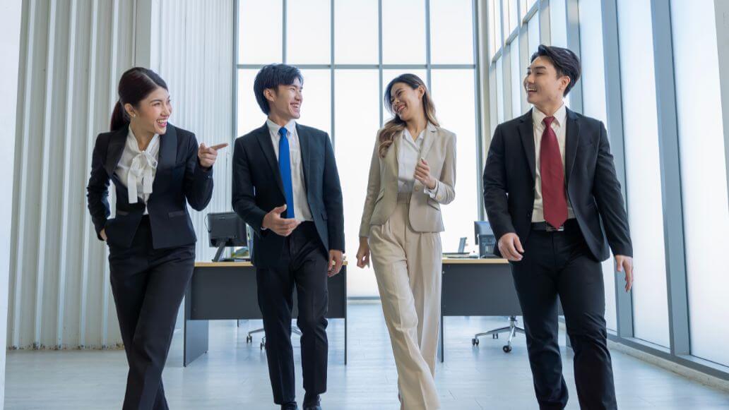 並んでオフィスを歩くアジア人のオフィスワーカーたち