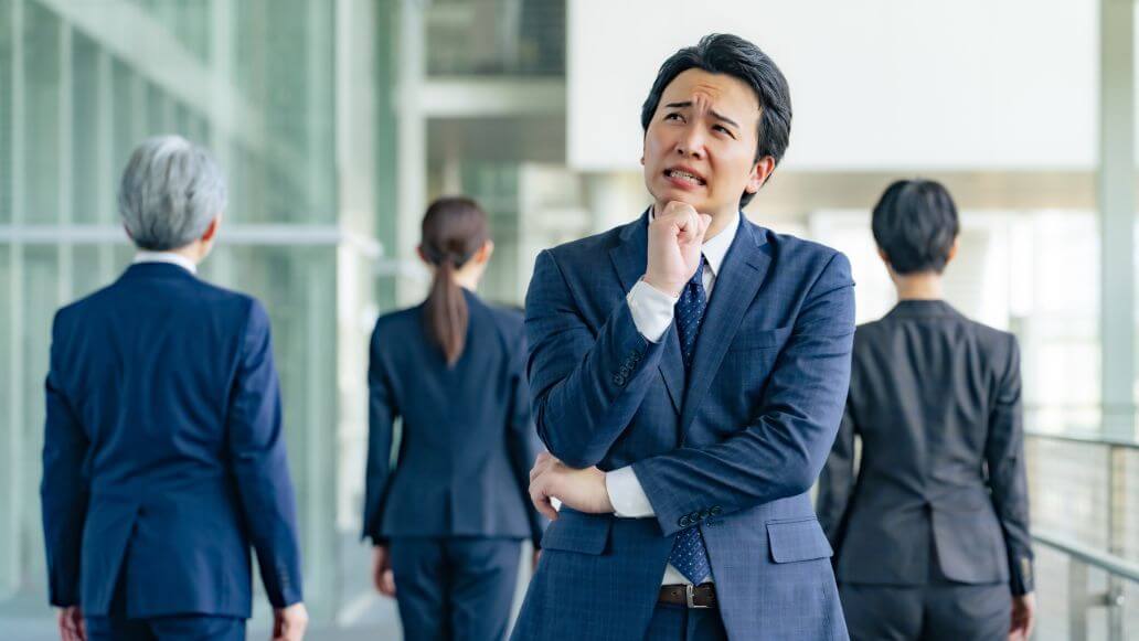 同僚に背を向けることを心配している男性のビジネスマン