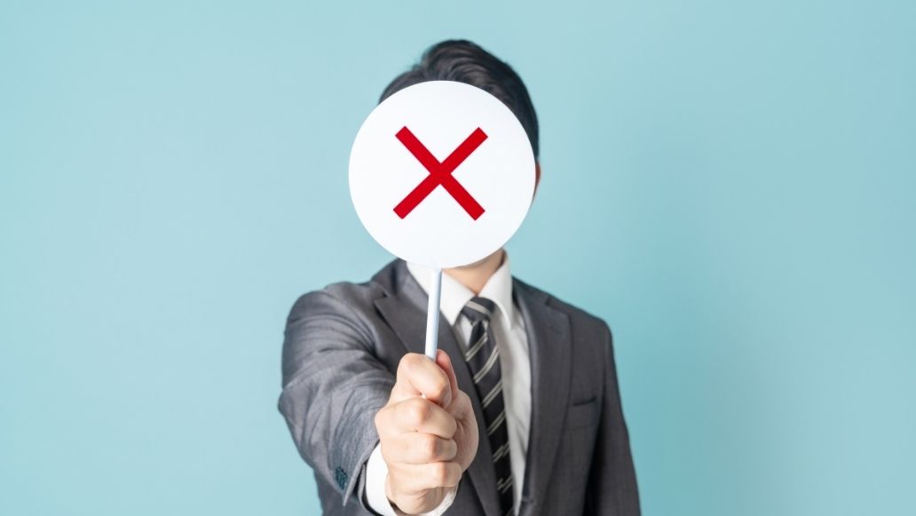 バツマークを持った男性