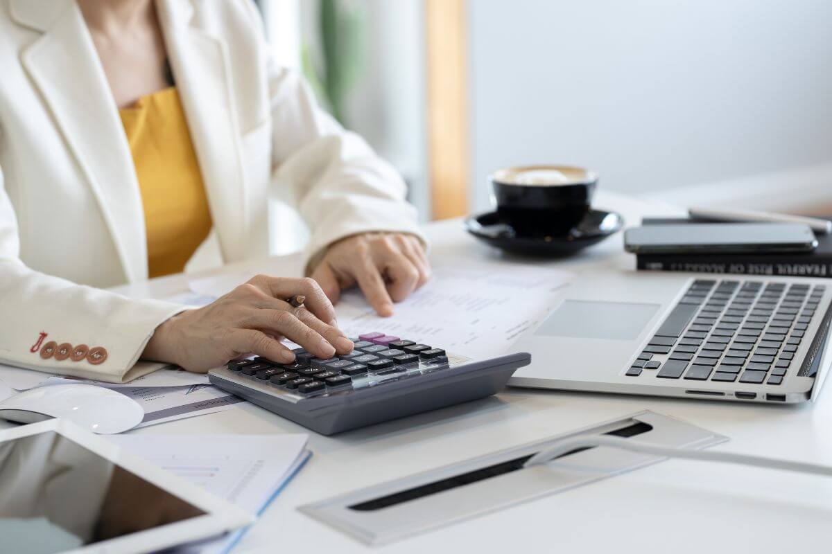 デスクで電卓とPCを操作する女性