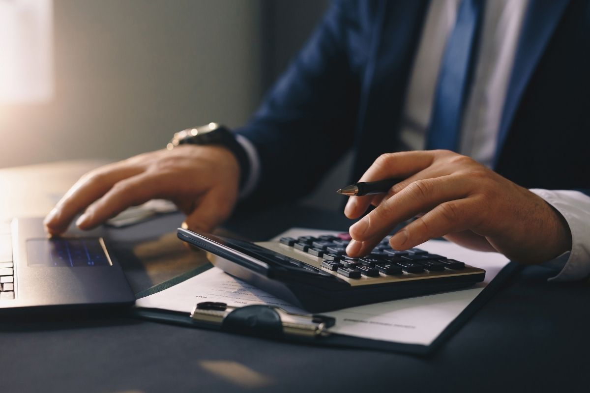 電卓で計算しながらPC作業する男性