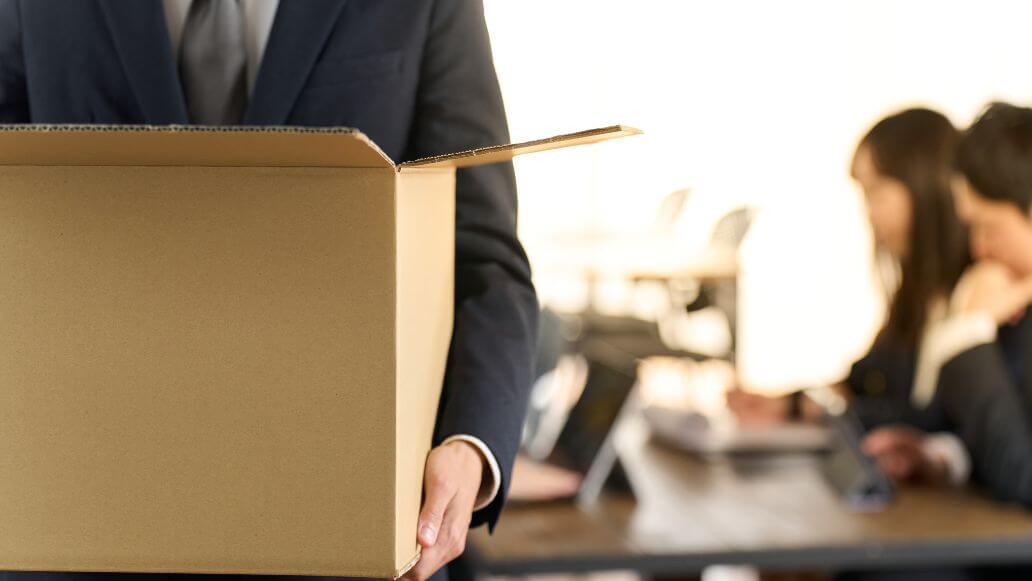 荷物をまとめてオフィスを去る男性