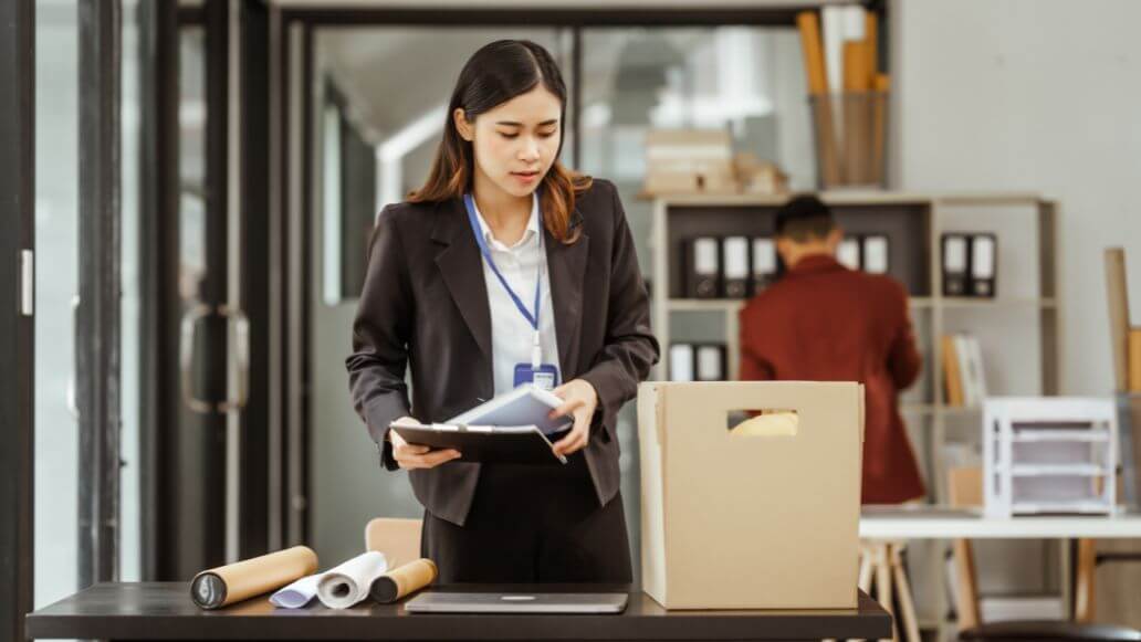 自分のデスクの荷物をまとめるスーツの女性