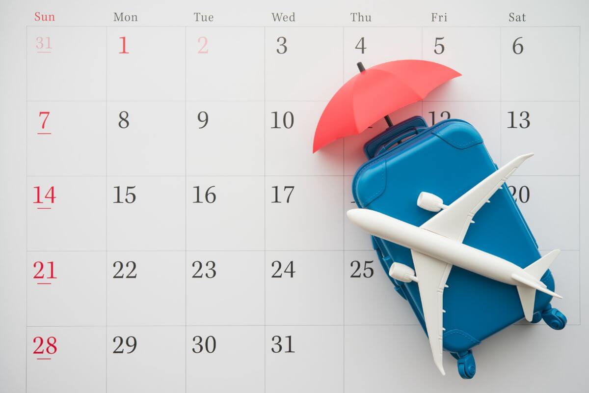 白いカレンダー背景に飛行機、スーツケース、傘