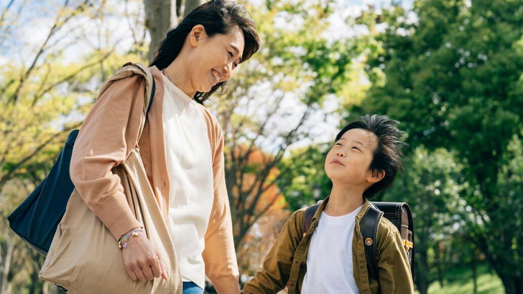 手をつないで歩いている小学生の男の子と母親