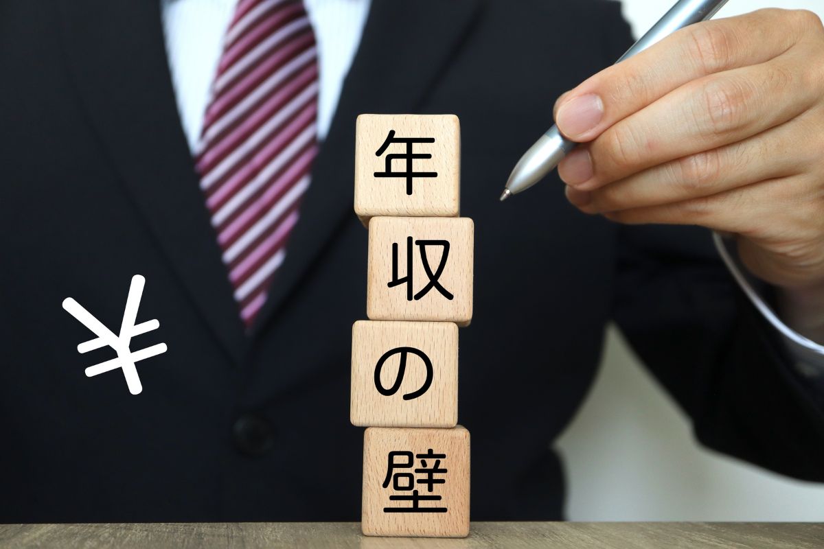 年収の壁のブロックをさす男性