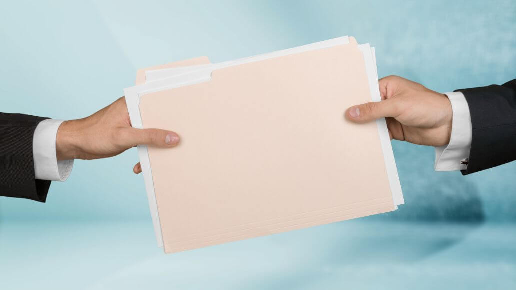紙のファイルを手渡すビジネスマン