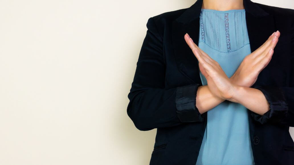 腕でバツを作るスーツのビジネスパーソン