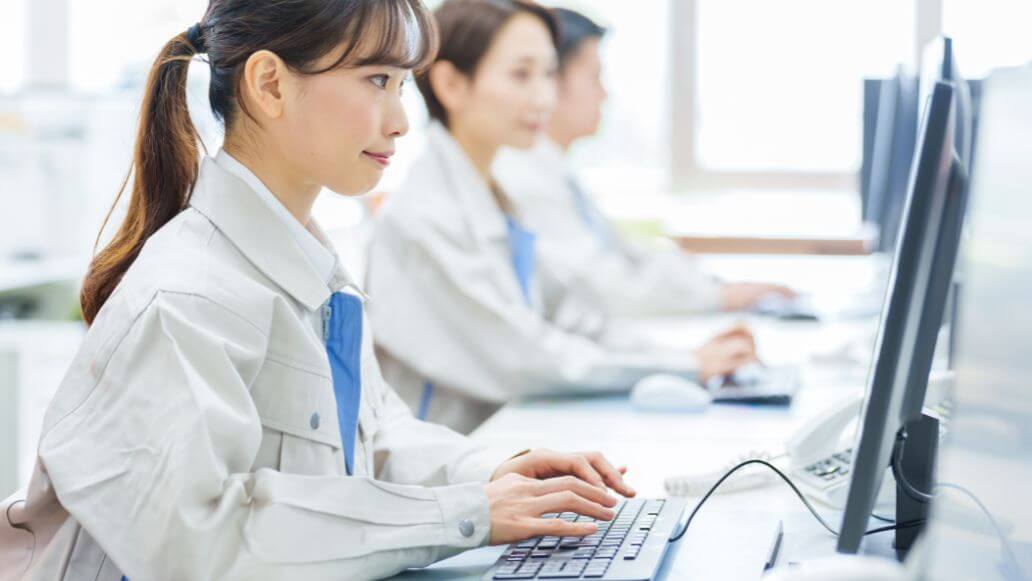 オフィスでコンピューターを使って作業着を着たアジアの若い女性エンジニア