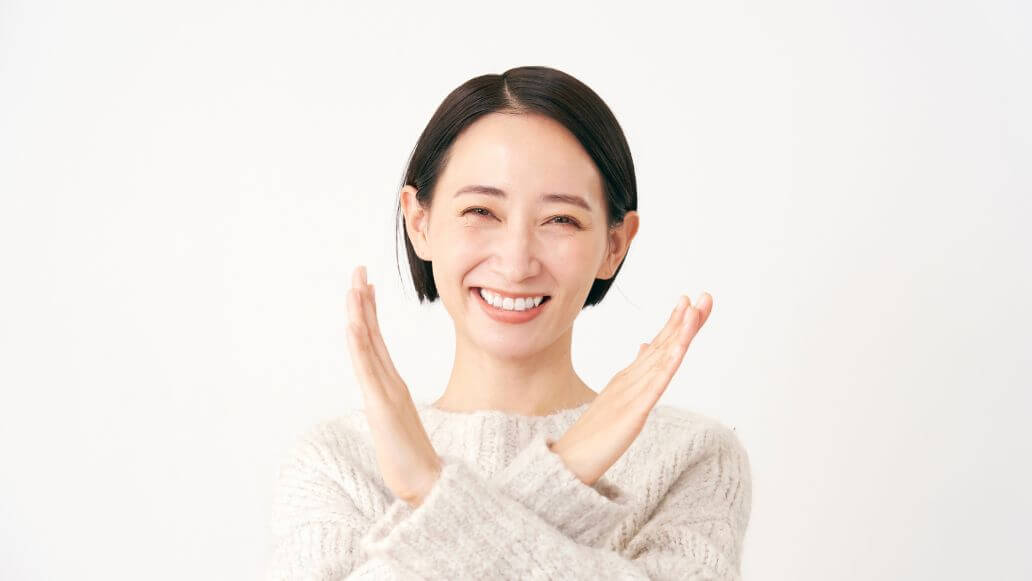 腕でバツ印を作る女性