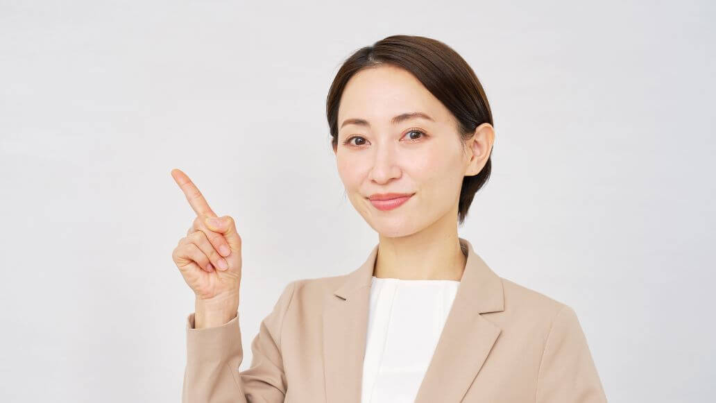 人差し指を立てるスーツを着た女性