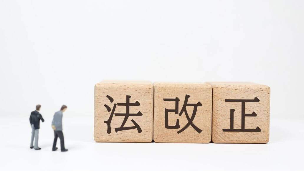 法改正を象徴する木のブロックとミニチュアビジネスマン
